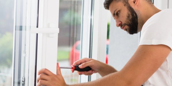 A man repairs a window using a screwdriver, focused on the task in a bright, modern interior for Window Repairs Dublin